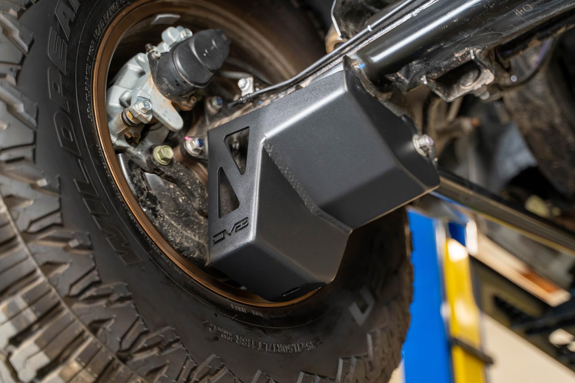 Rear Shock & Link Skid Plates DV8 for 2024 Toyota Tacoma | Protects Lower Shock Mount & Link | Built-in Drain Holes | Single Piece Design | Fully Bolt-On Installation | Black Powder Coat | 4mm Steel